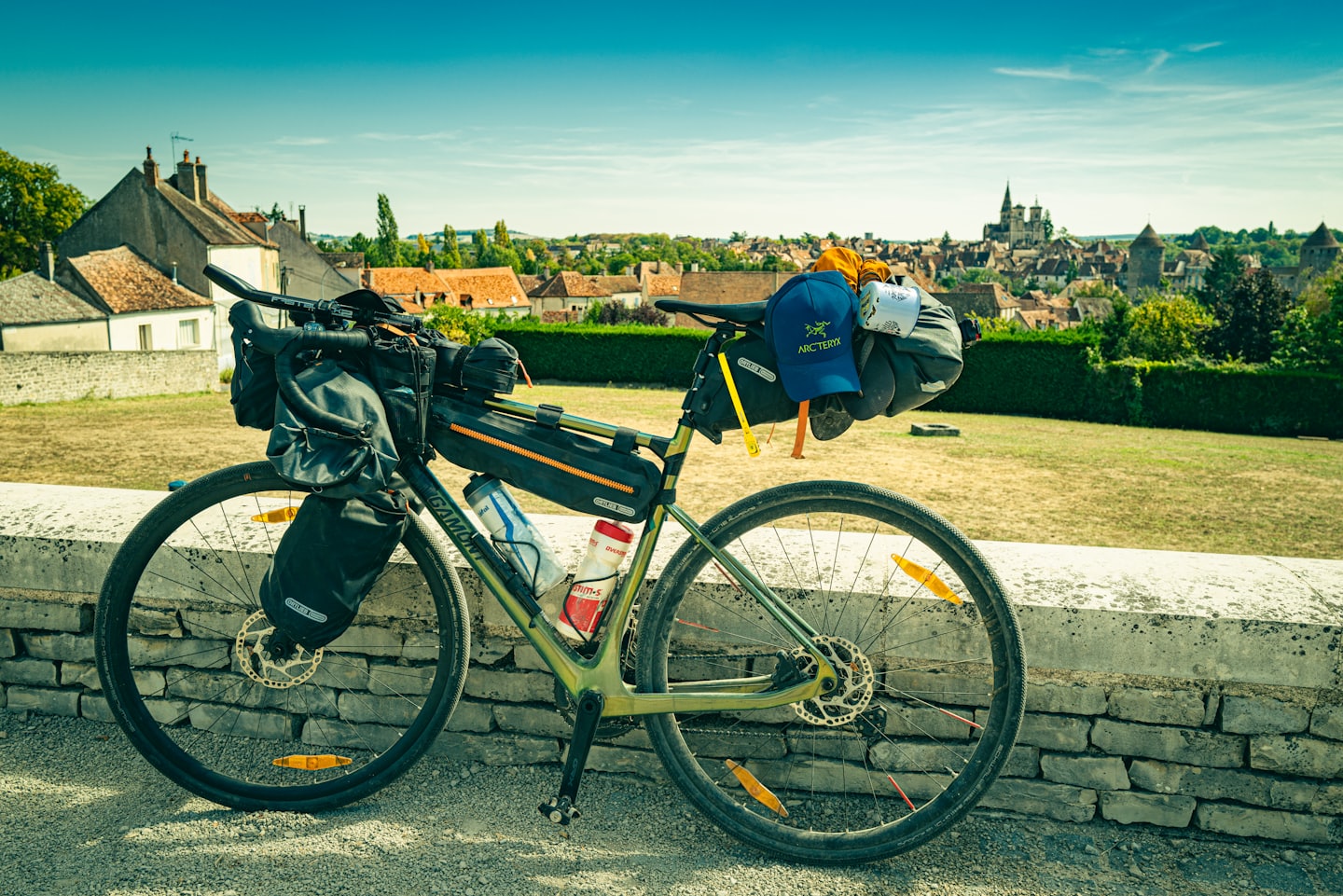 Zaparkowany rower bikepackingowy z bagażem przy zabytkowym murze europejskiego miasta.
